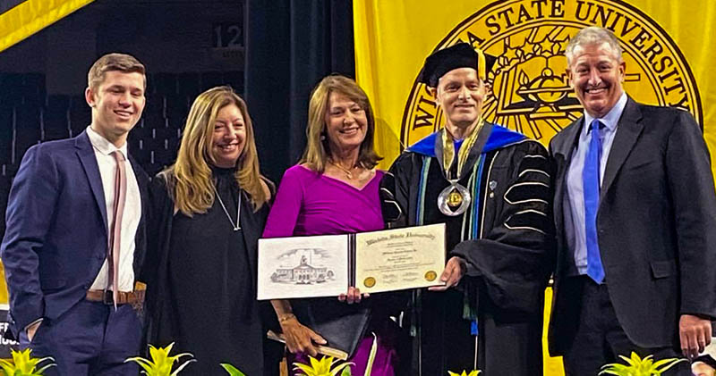 Members of Bill Cohen’s family who attended the May 15 ceremony conferring an honorary doctorate upon him included, from left, his youngest grandson Jonah Cohen, daughter Susan Cohen-Butler, wife Dorothy Cohen, WSU President Rick Muma and son Rob Cohen.