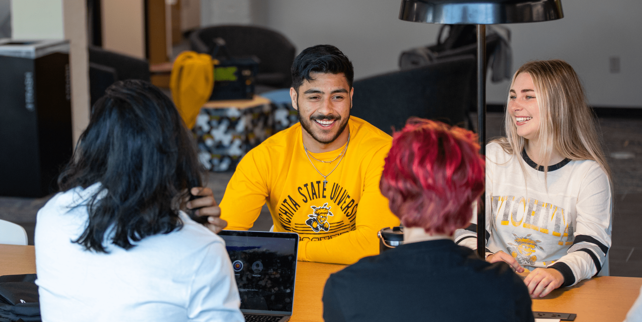 Four wichita state students conversing at a table