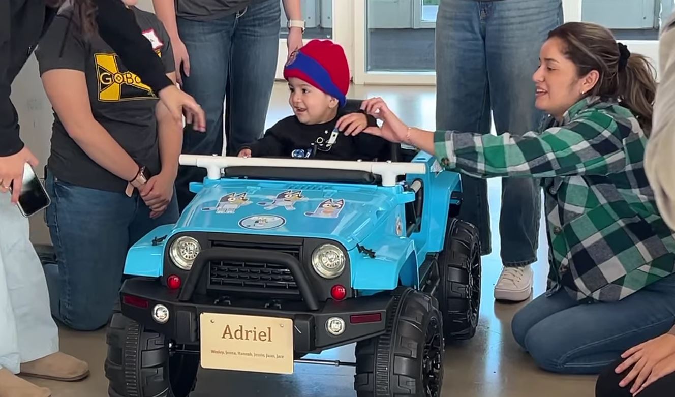 Students help a child operate his toy car