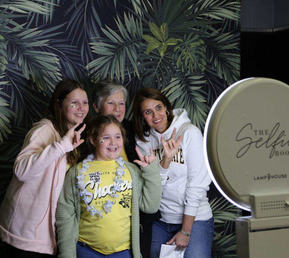 Three generations of women standing together smiling in a photobooth