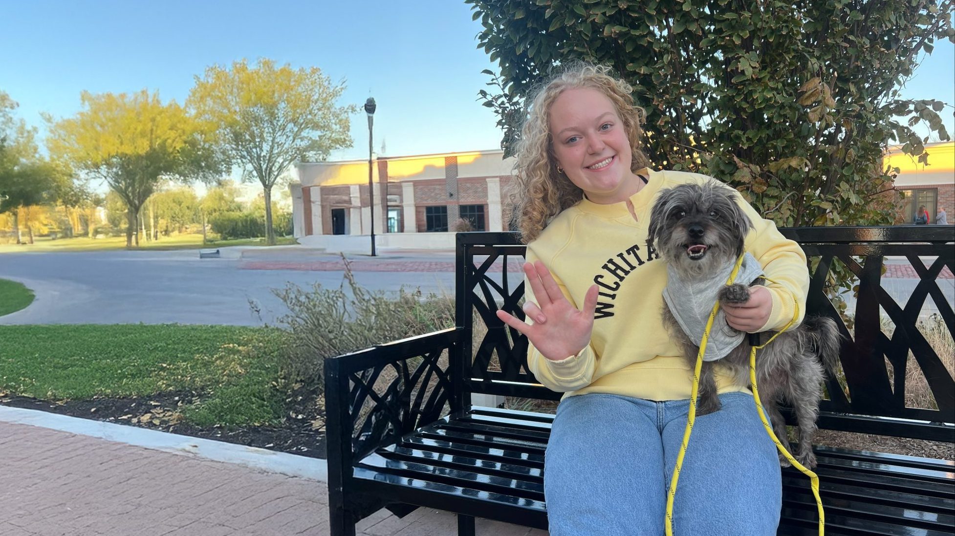 Wichita State student emily streeter sitting on a park bench with her dog